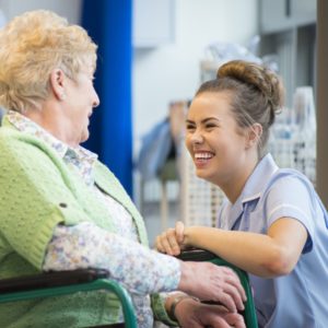 senior woman laughing with nurse on the ward or nursing home