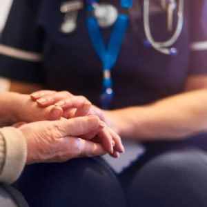 A female nurse consoles a senior patient at home